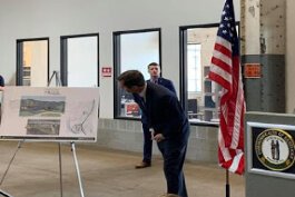 Kentucky Gov. Andy Beshear looks at plans for Wilder's redevelopment during his announcement of a grant for the project.