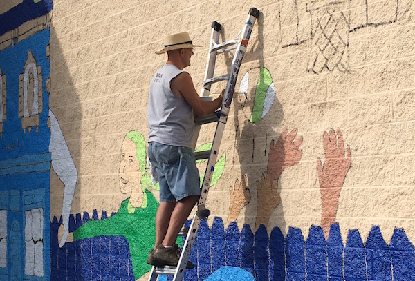Local artist Kevin T. Kelly works on the “Love the Cov” mural 