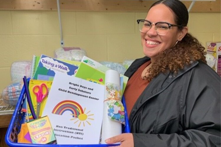 Bright Days Child Development Center staff member, Kasi, with “to go” curriculum for parents to continue to make developmental progress with children while Bright Days and Scholar House are closed.